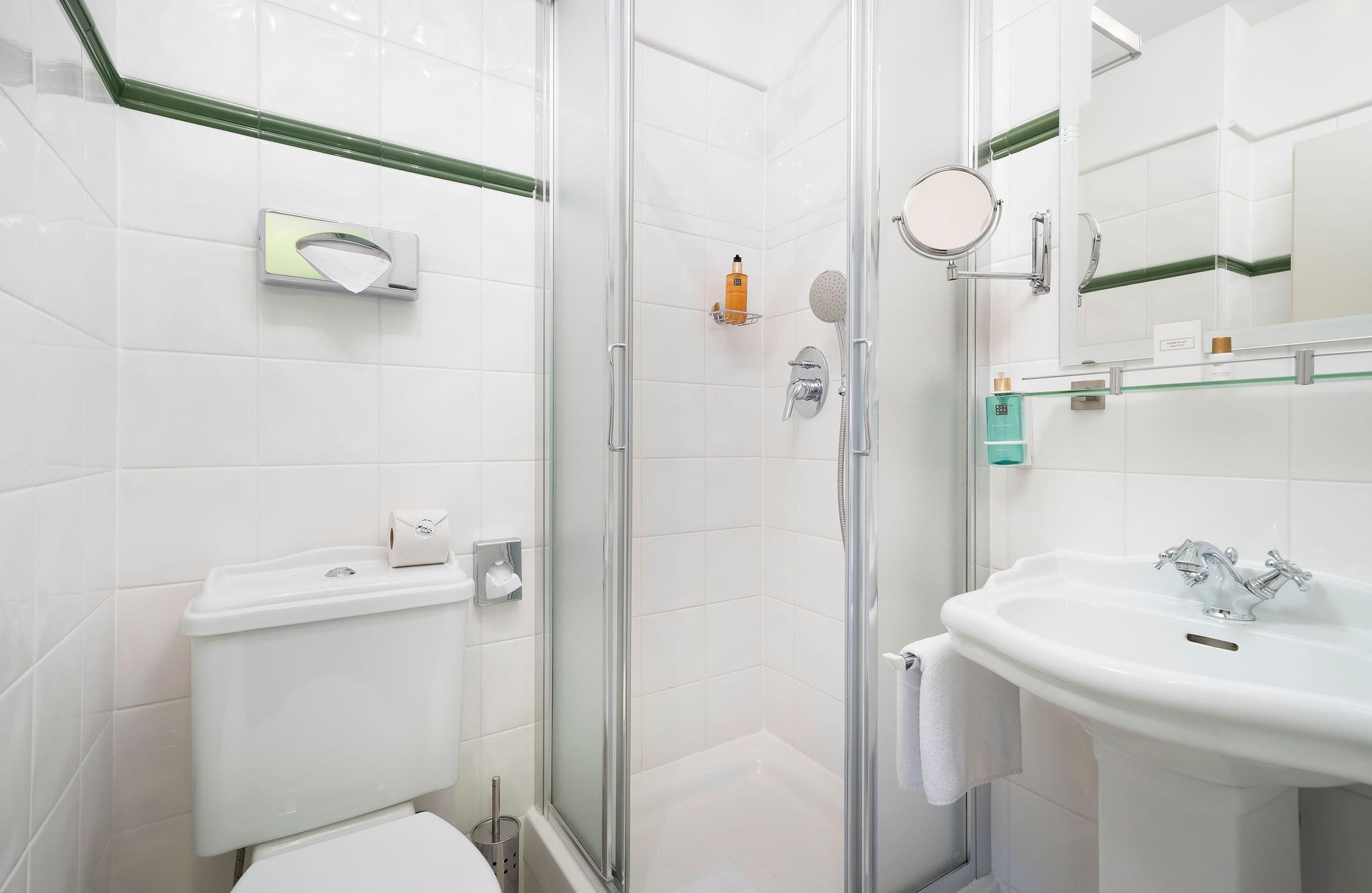 A bathroom with a toilet, a shower enclosure, a sink, and a mirror.