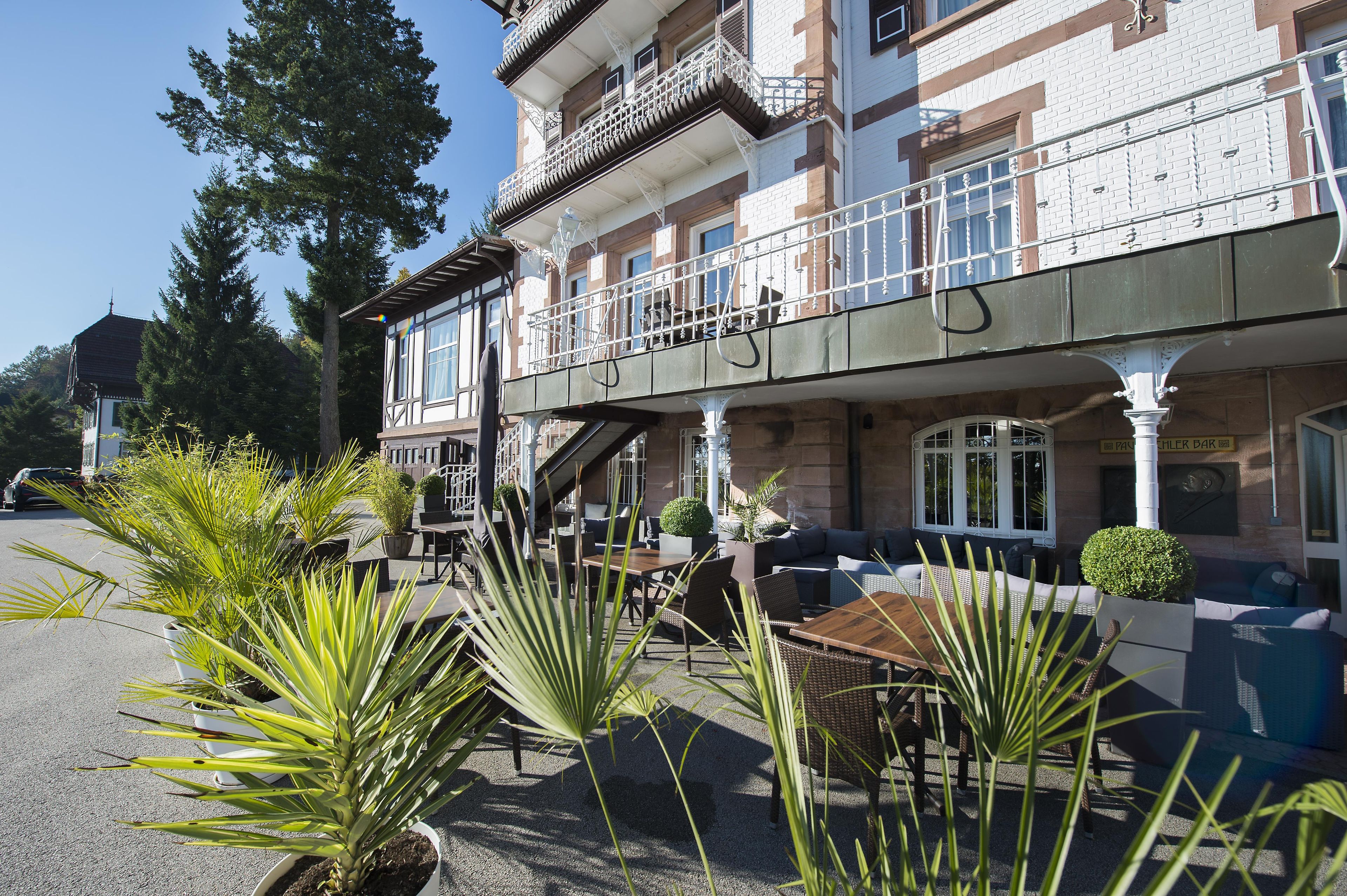 Ein Gebäude mit Balkon, Außenbestuhlung und einer Bar-Beschilderung.