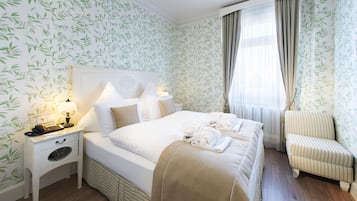 Una habitación de hotel con una cama, mesita de noche, lámpara y una silla.