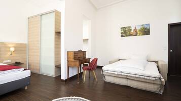 A modern hotel room with a bed, a desk, a chair, and a wardrobe.
