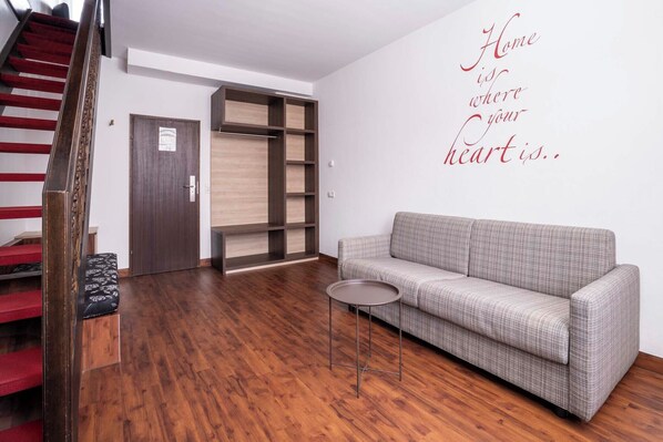 A modern living room with a wooden staircase, a grey sofa, and a small round table.