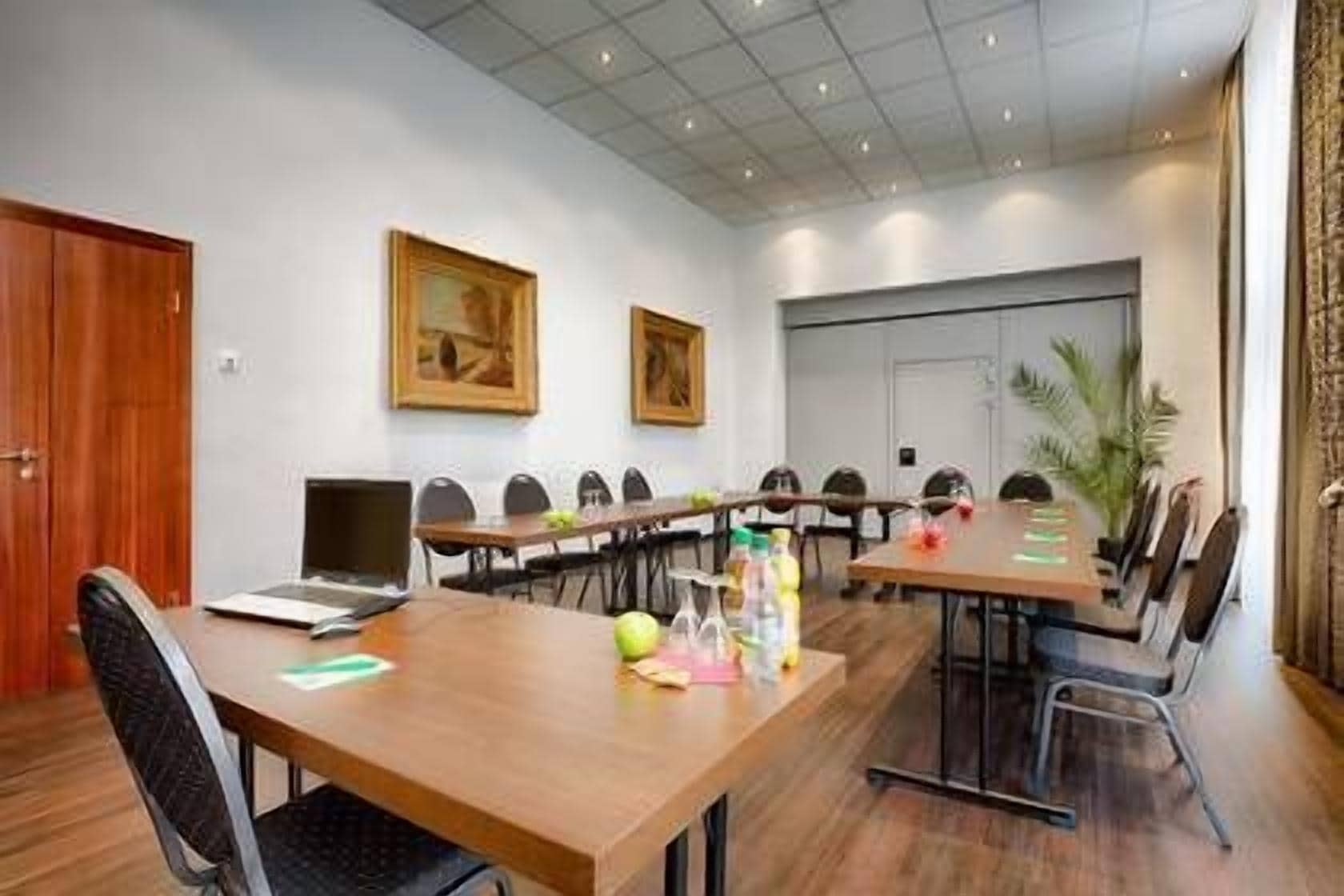 A conference room with a long table, chairs, a laptop, and a few personal items on the table.