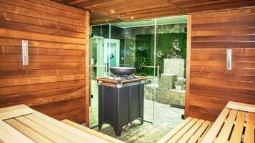 Relax in a serene sauna room with a heated table and glass door leading to a tranquil outdoor space.