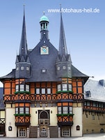 Un edificio storico con una torre dell'orologio, diverse guglie e una facciata a graticcio tradizionale.