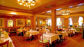 Un restaurante con varias mesas y sillas, paneles de madera y una alfombra escocesa.