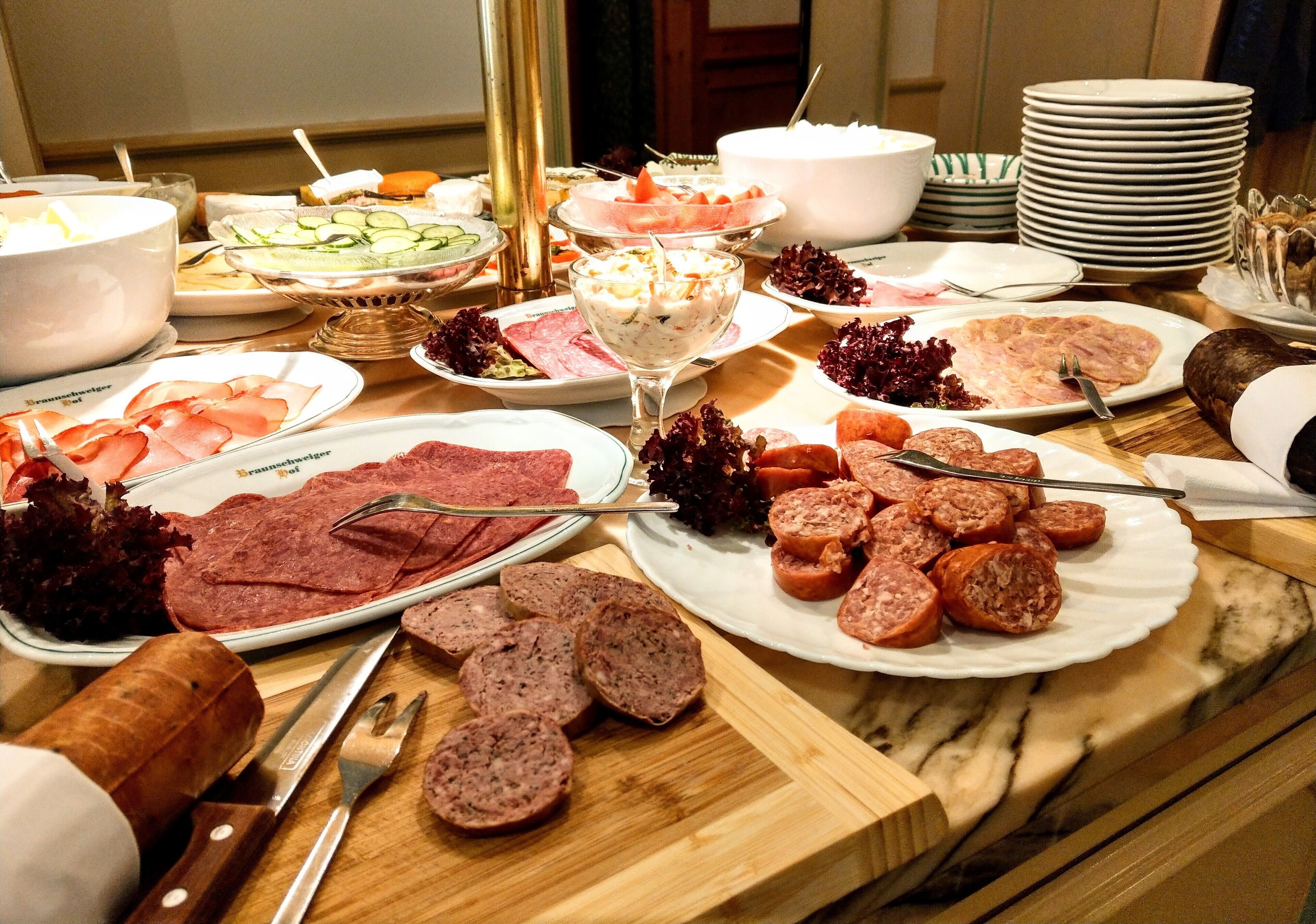 A buffet table with various food items including meats, salads, and a large bowl of soup.