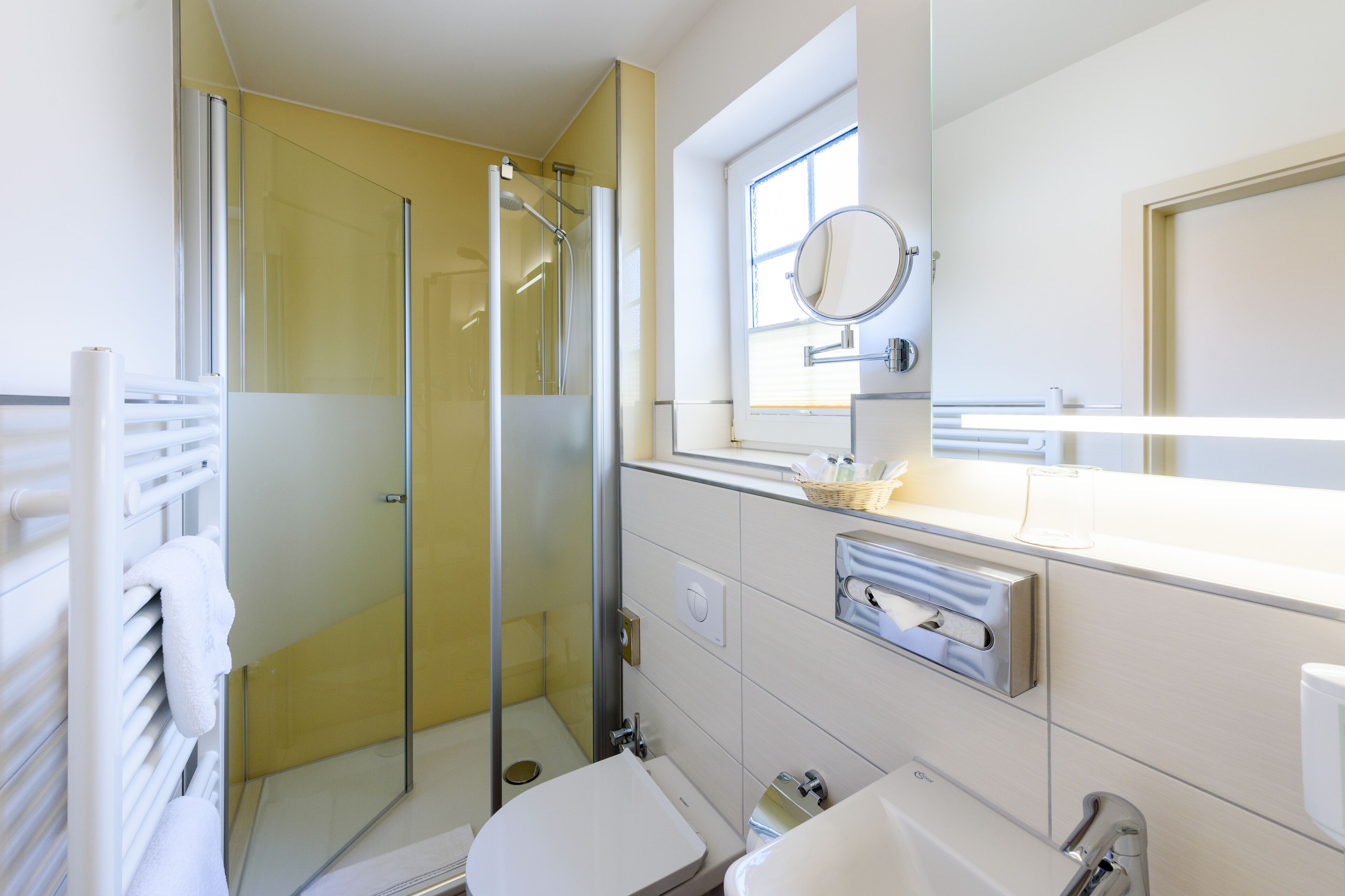 A modern bathroom with a glass-enclosed shower, a white sink, and a mirror above the sink.