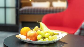 Een fruitschaal op een tafel, met een rode stoel op de achtergrond.