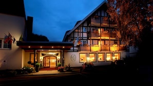A traditional European hotel with a prominent entrance, multiple balconies, and a well-lit facade.