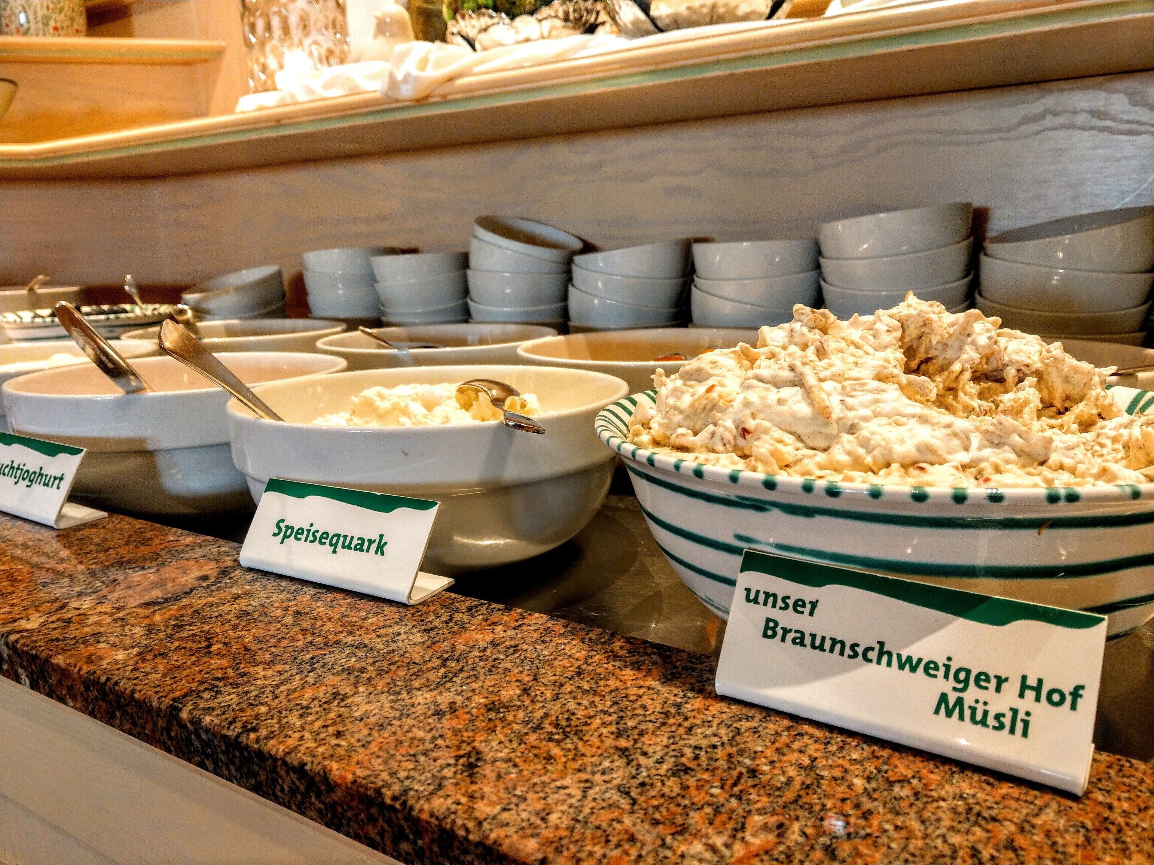 Ein Buffet mit ausgewiesenen Speisen, darunter 'Spießequark' und 'Unser Braunschweiger Hof Müslis'.