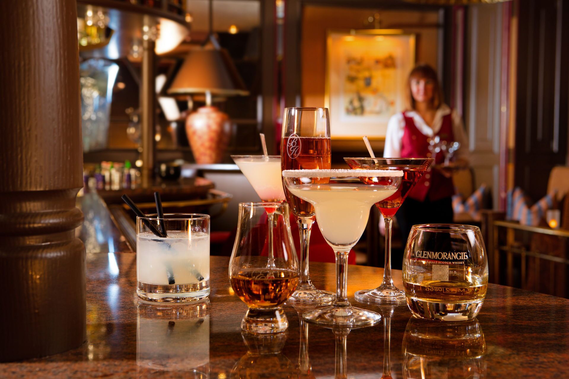 En bar med ett urval av olika sorters drycker i glas, inklusive en flaska Glenmorangie-whisky.