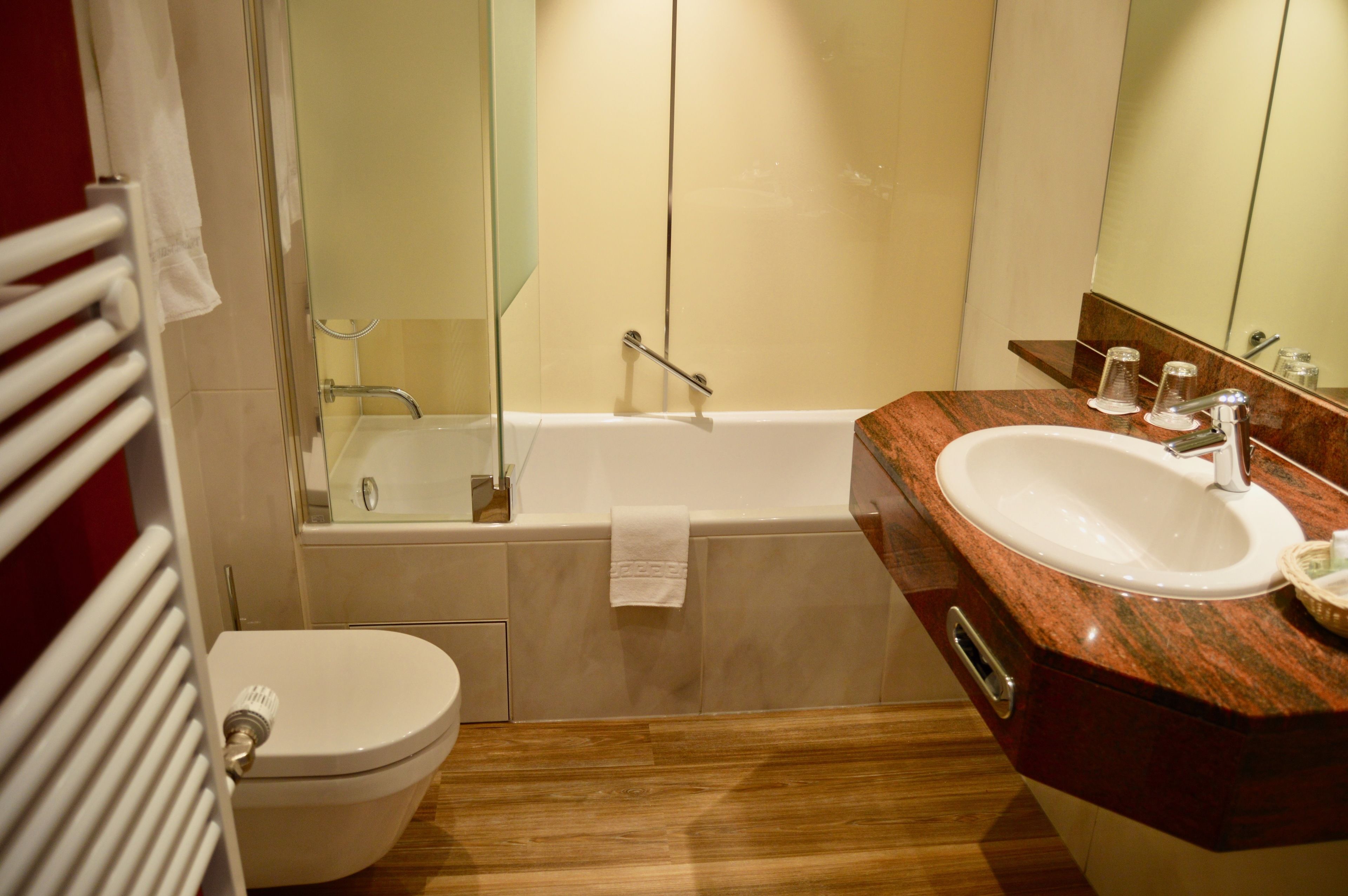 A bathroom with a toilet, a sink, a bathtub, and a mirror.