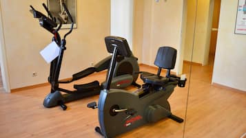 A home gym with two stationary bikes and a treadmill.