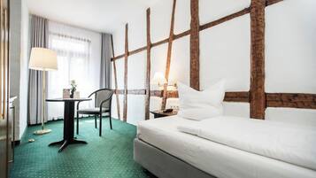A hotel room with a bed, a desk, a chair, and a lamp.