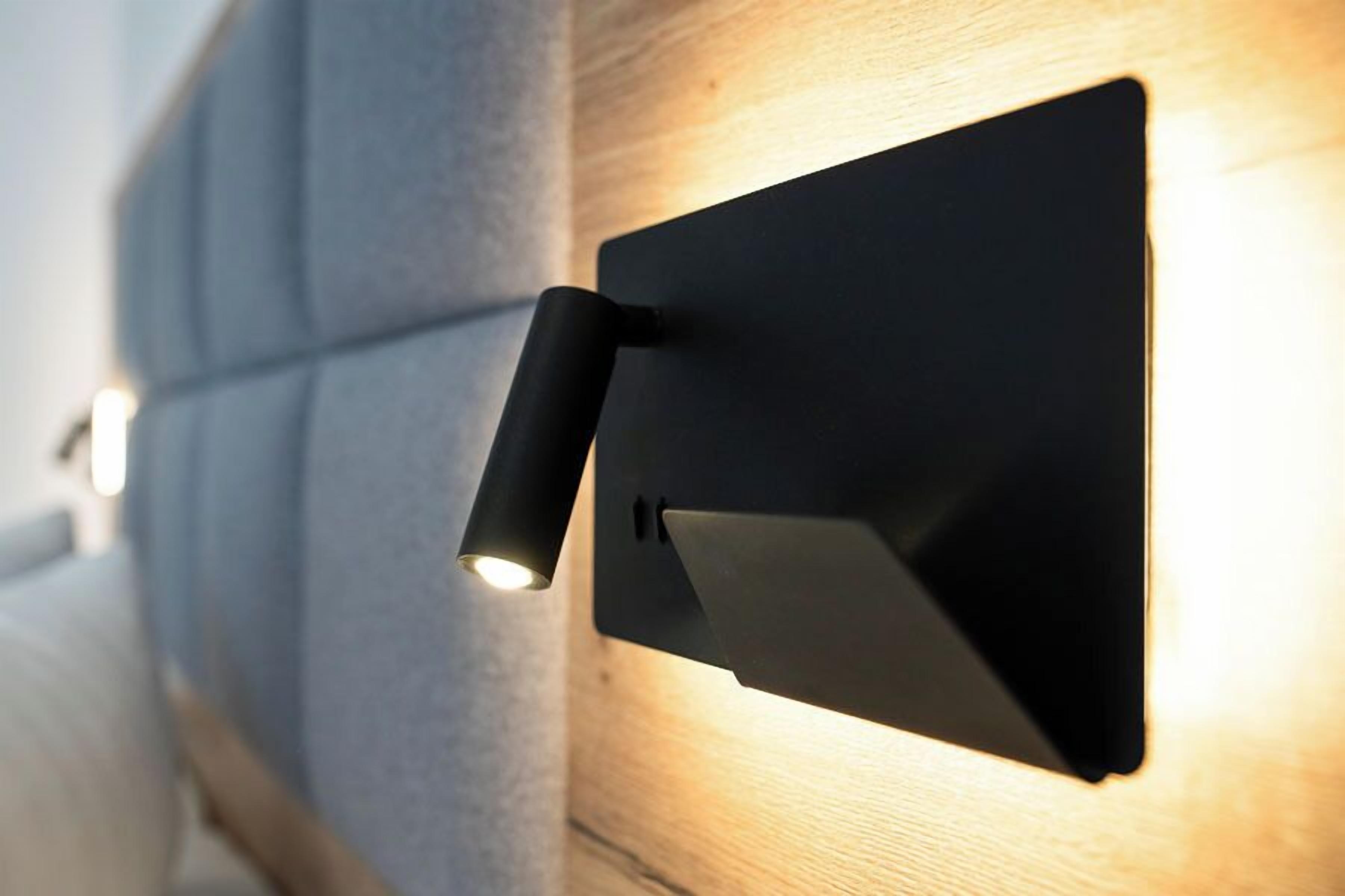 A wall-mounted light fixture with a cylindrical shade and a flat panel.