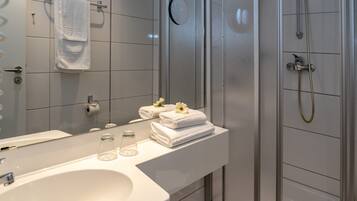 A modern bathroom with a large mirror, white sink, and a glass shower enclosure.