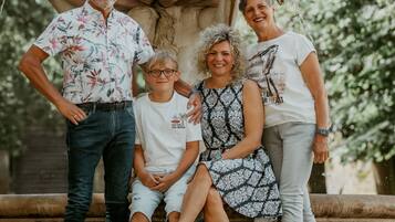 A family of four posing in front of a fountain with a lion statue, surrounded by yellow flowers.