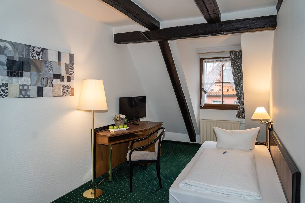 Una habitación de hotel con cama, escritorio, silla y televisor.