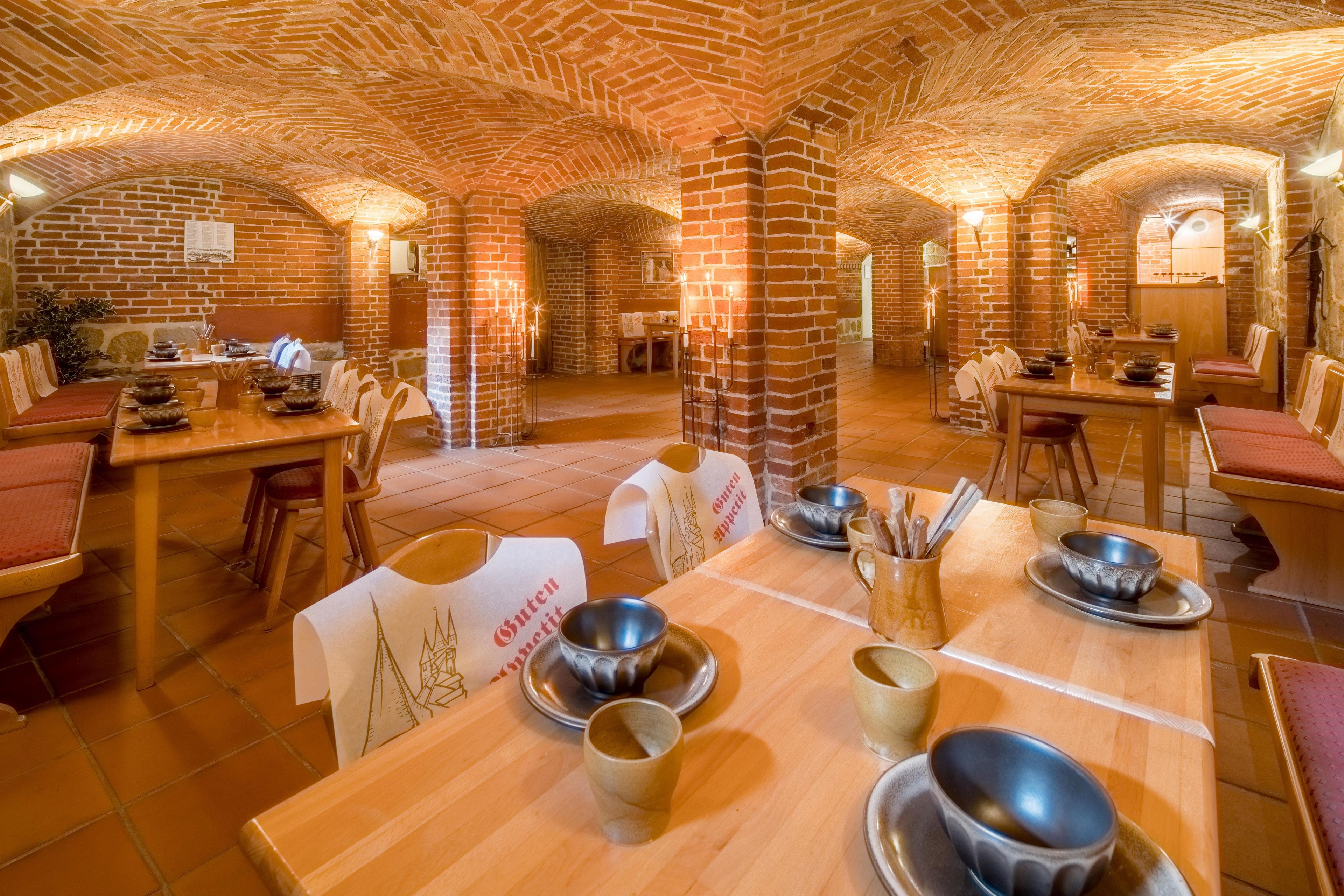 A restaurant with brick walls and wooden tables, featuring candle-lit tables and a menu stand.