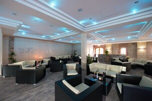 Amplia sala de estar con diversas opciones de asientos, incluyendo sofás y sillones, organizados alrededor de una mesa central.