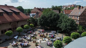 An outdoor courtyard with stone paving, surrounded by trees and buildings with red-tiled roofs. - Best Western Hotel Schlossmuehle (Quedlinburg)