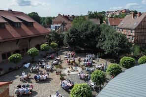 An outdoor courtyard with stone paving, surrounded by trees and buildings with red-tiled roofs. - Best Western Hotel Schlossmuehle (Quedlinburg)