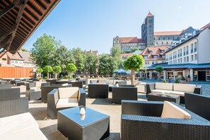An outdoor seating area with wicker furniture and a view of historic buildings in the background. - Best Western Hotel Schlossmuehle (Quedlinburg)