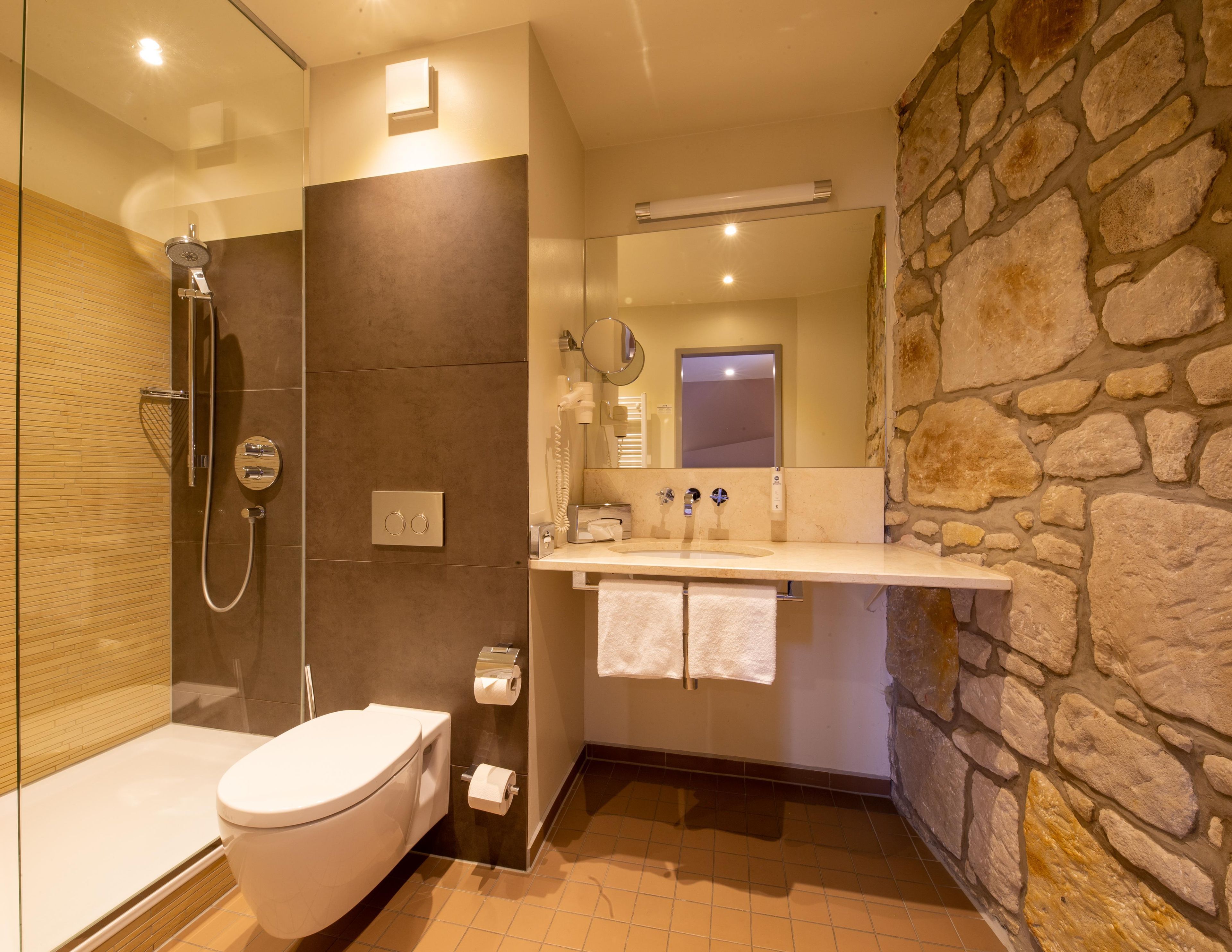 Een moderne badkamer met douche, toilet en wastafel.