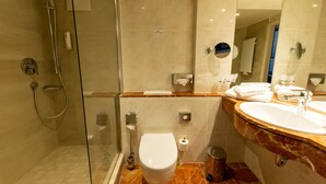 A modern bathroom with a glass-enclosed shower, a toilet, a sink with a marble countertop, and a mirror. - Best Western Hotel Schlossmuehle (Quedlinburg)