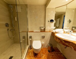 A modern bathroom with a glass-enclosed shower, a toilet, a sink with a marble countertop, and a mirror. - Best Western Hotel Schlossmuehle (Quedlinburg)