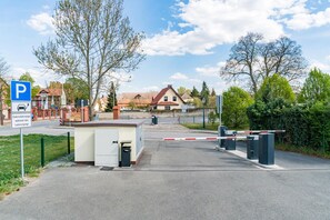 A gated parking area with a blue parking sign, a small utility shed, and a building with a red roof in the background. - Best Western Hotel Schlossmuehle (Quedlinburg)