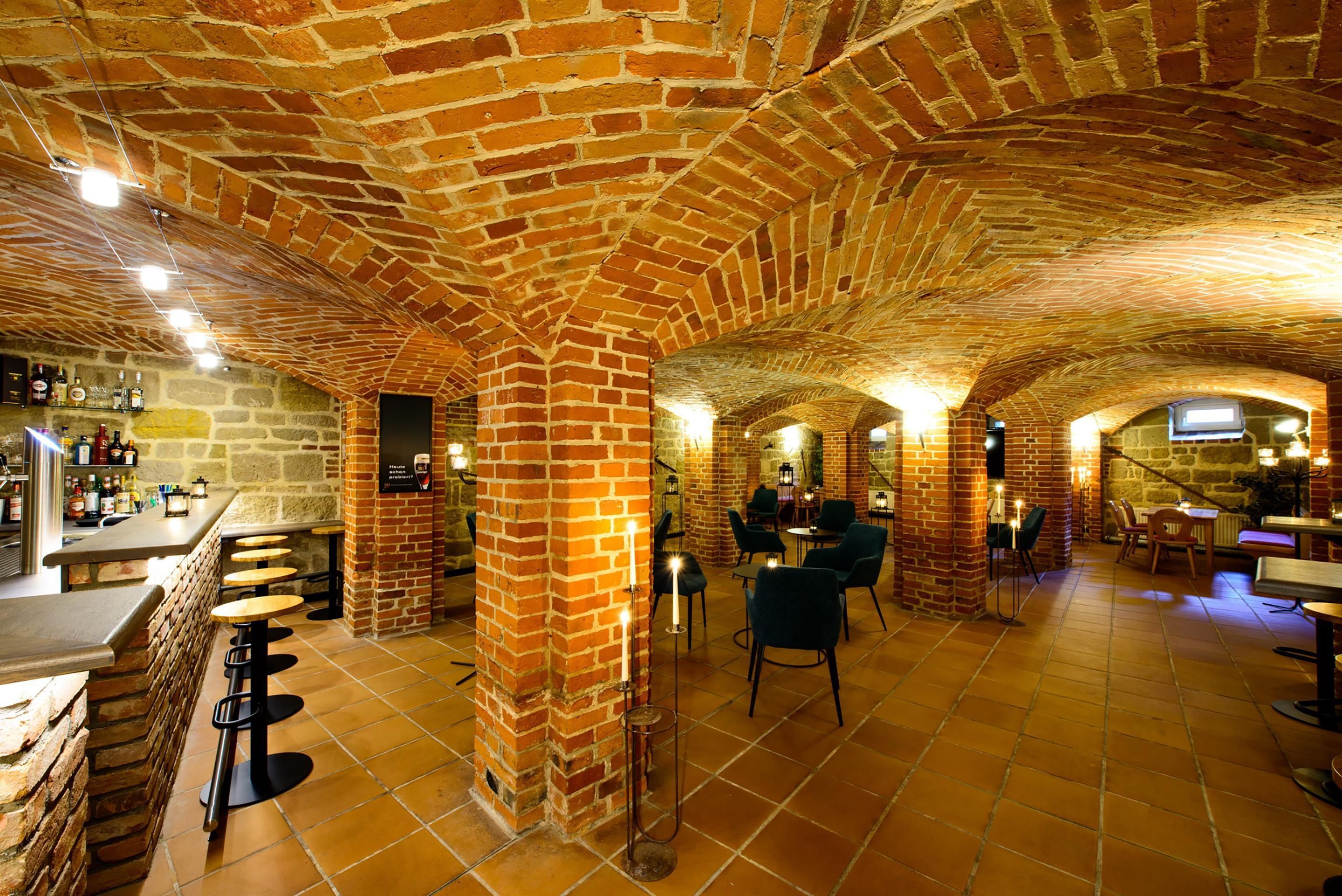 Un intérieur aux murs de briques, avec un bar, des sièges et des tables.