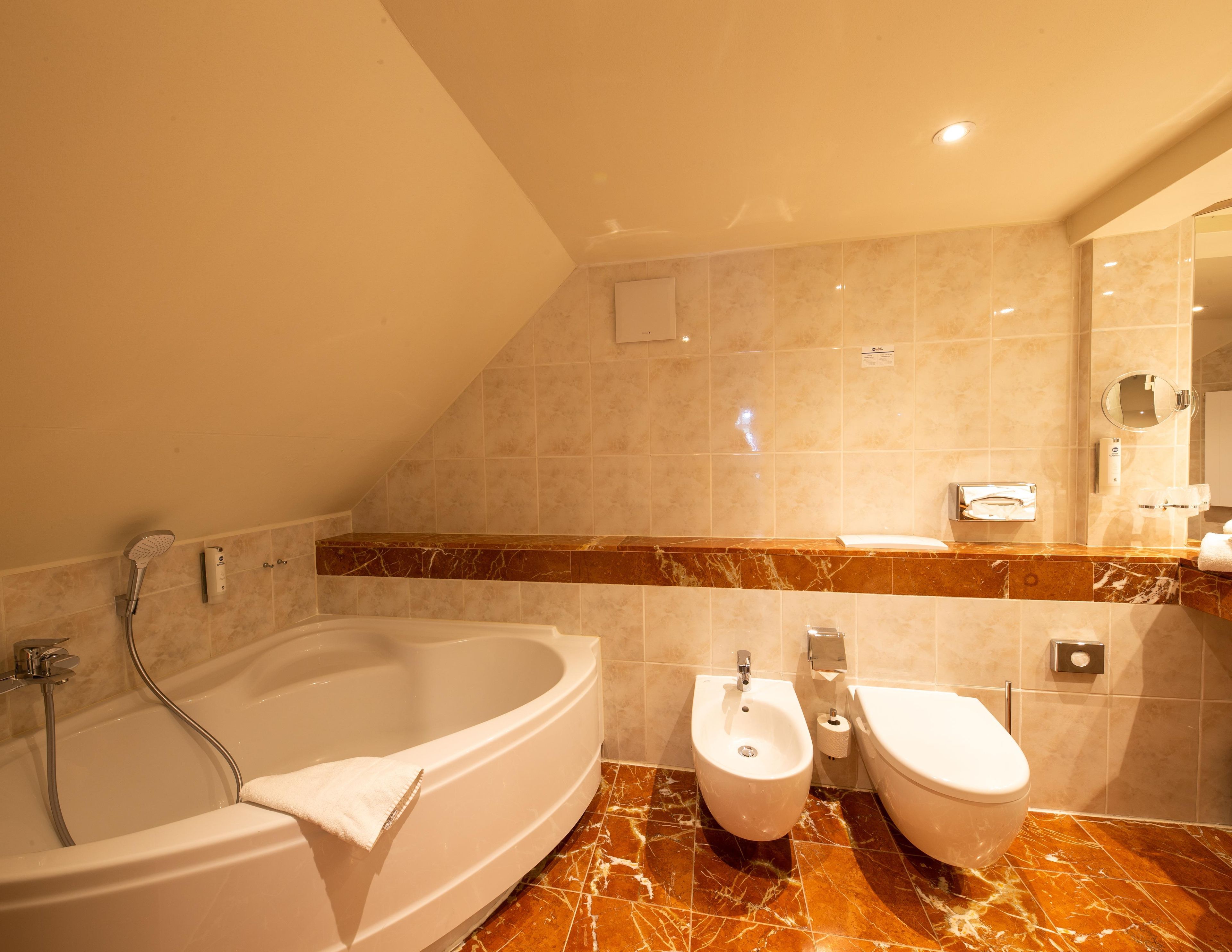 A modern bathroom with a bathtub, a bidet, and a toilet.