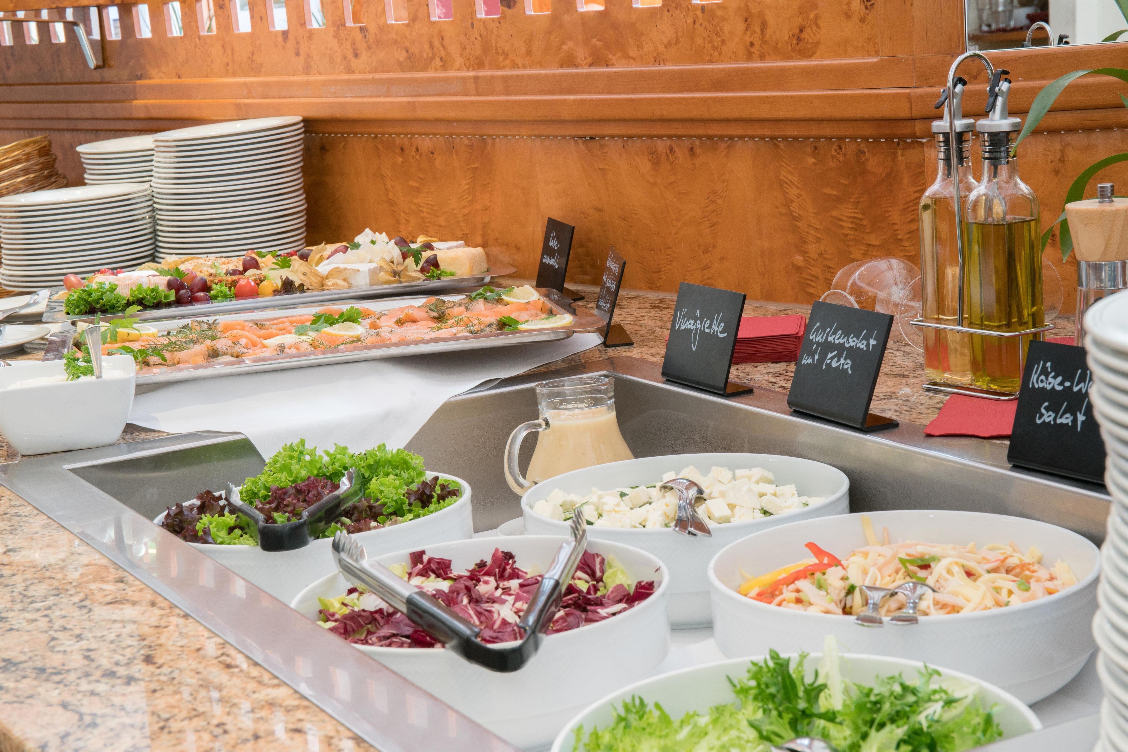 A buffet with various food options including salads, pasta, and seafood.