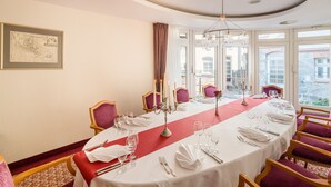 A dining room with a long table set for six, red and white tablecloths, and a chandelier. - Best Western Hotel Schlossmuehle (Quedlinburg)