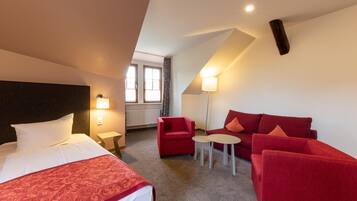 Ein Hotelzimmer mit einem Bett, einem roten Sofa, einem kleinen Tisch und einer Lampe.