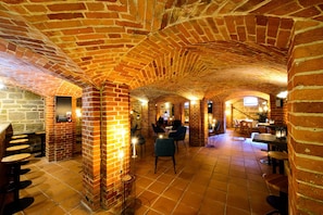 Un intérieur caractérisé par des arches en briques, un sol carrelé et des tables accompagnées de chaises.