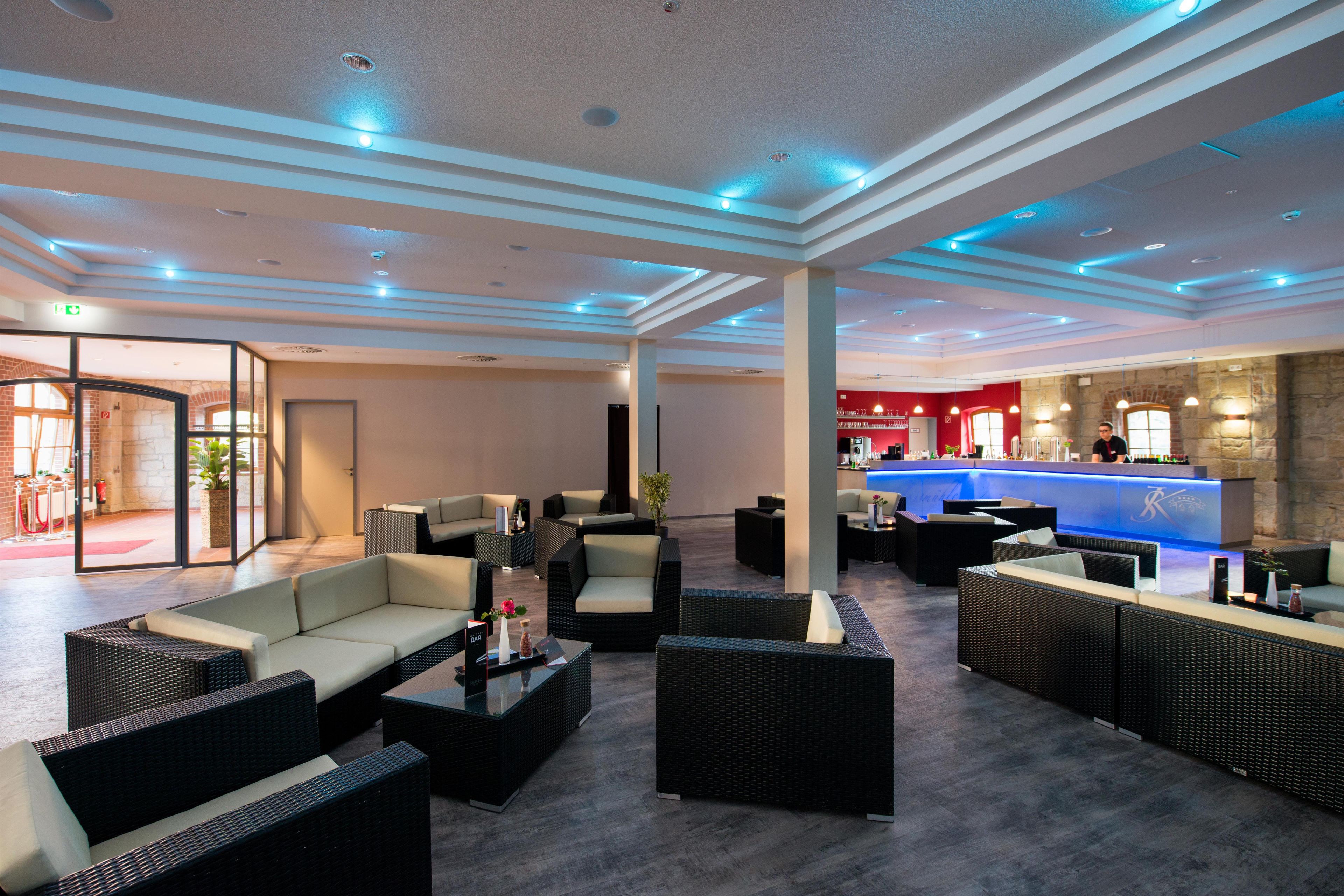 A spacious lobby with modern furniture, a reception desk, and a bar area.