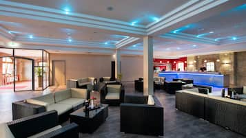 A spacious lobby with modern furniture, a reception desk, and a bar area.