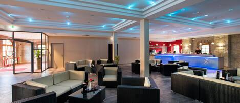 A spacious lobby with modern furniture, a reception desk, and a bar area.