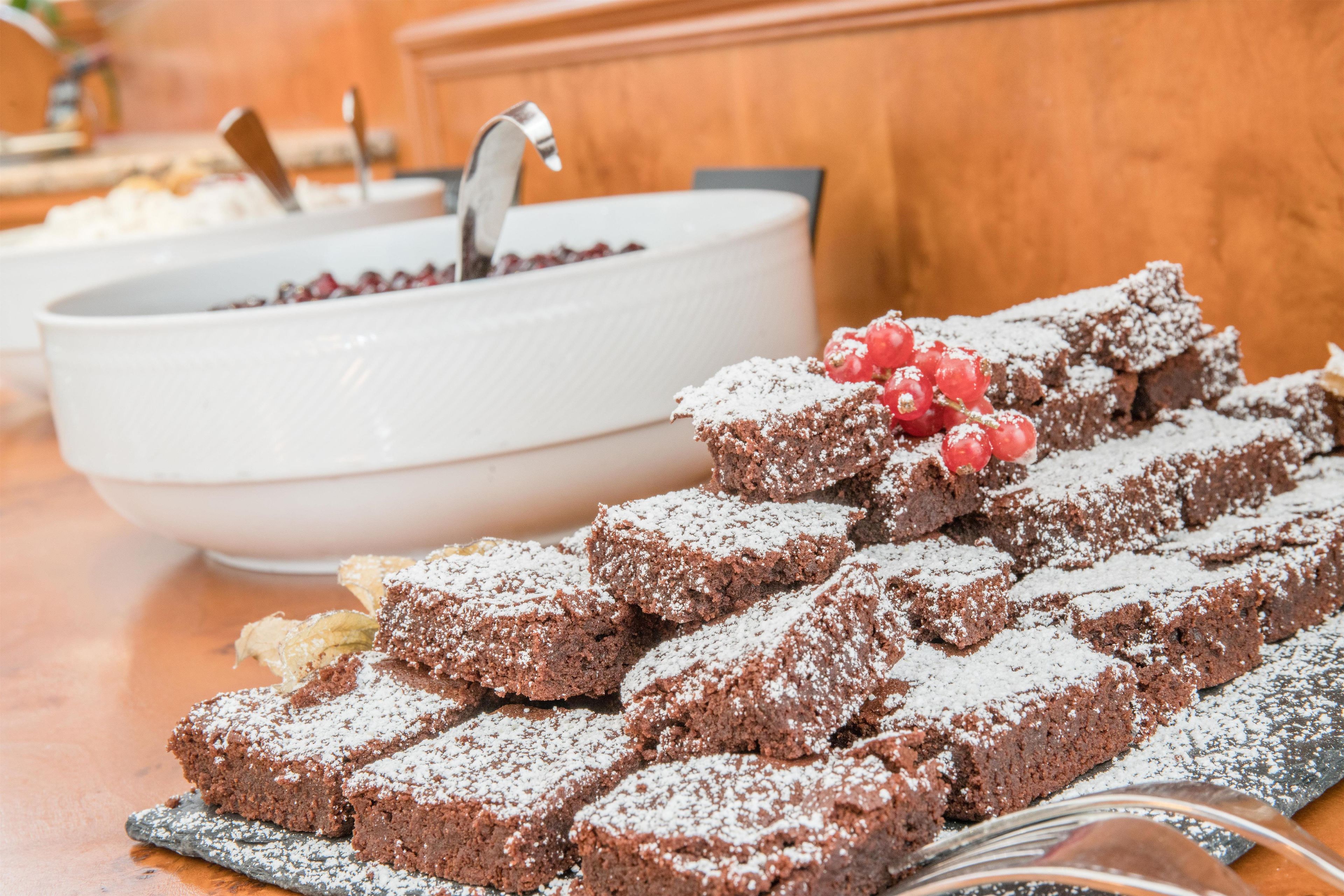 Un bufé de postres con brownies y frutos rojos.
