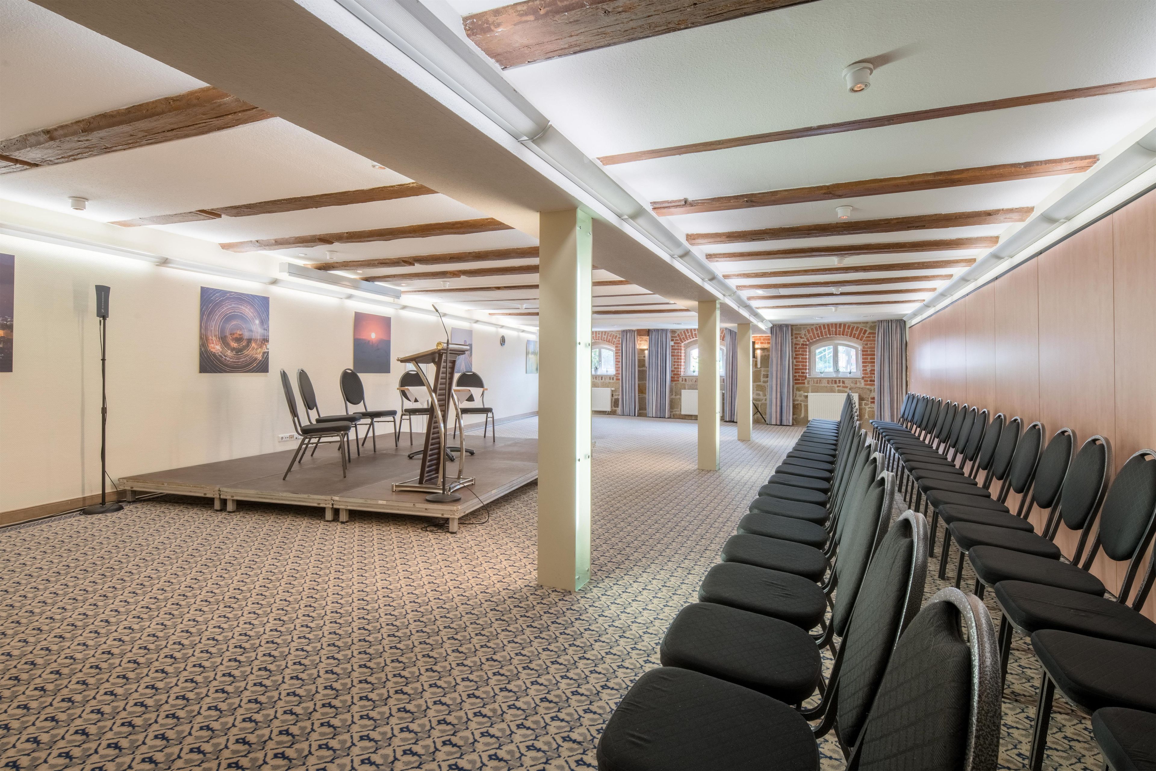 A conference room with a long table, chairs, and a stage.