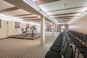 Un salón de conferencias con una mesa larga, sillas y un escenario.