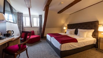 A hotel room with a bed, desk, chair, and a window with curtains.