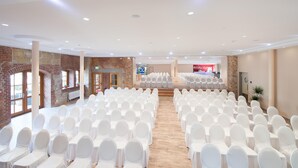A conference room with rows of white chairs, a stage at the front, and brick walls. - Best Western Hotel Schlossmuehle (Quedlinburg)