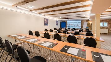 Une salle de conférence équipée de longues tables, de chaises et d’écrans de présentation.