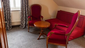 A room with a red sofa, a wooden chair, and a small round table. - Best Western Hotel Schlossmuehle (Quedlinburg)