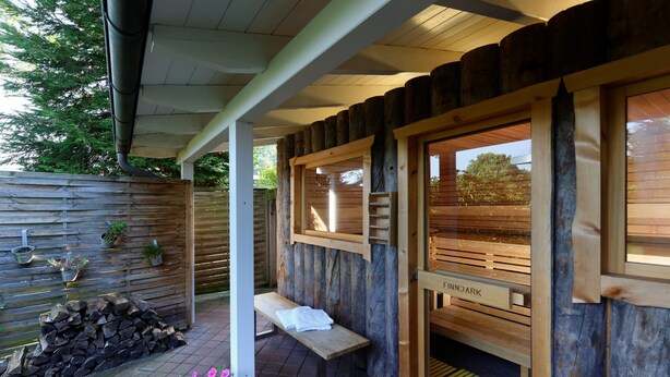 A wooden spa entrance with a bench and a sign reading "FINNDAARK". - Ringhotel Sellhorn (Hanstedt)