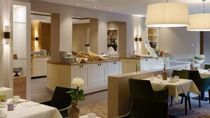 A modern hotel dining area with a central island, multiple tables, and a variety of breakfast items. - Ringhotel Sellhorn (Hanstedt)