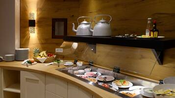 A buffet area with various food items, utensils, and teapots on a wooden counter.